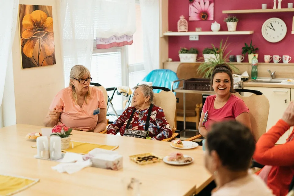 Older adults and other people gathered around a dining table.