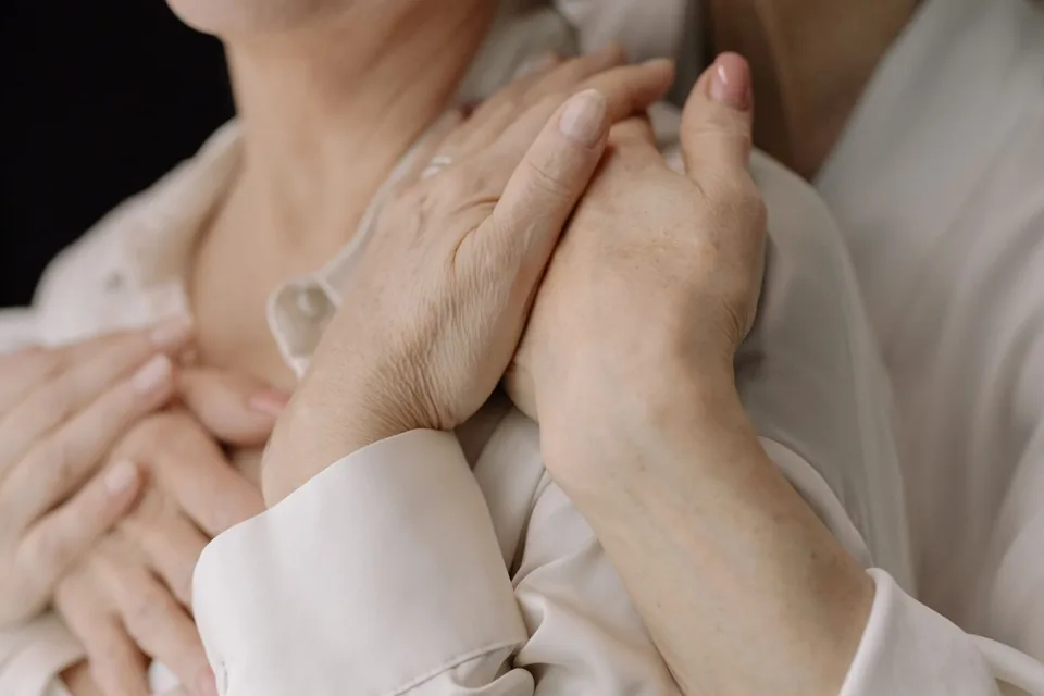 A close-up of hands resting together in a reassuring gesture.