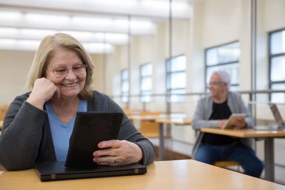 An older woman using a tablet during a group session.
