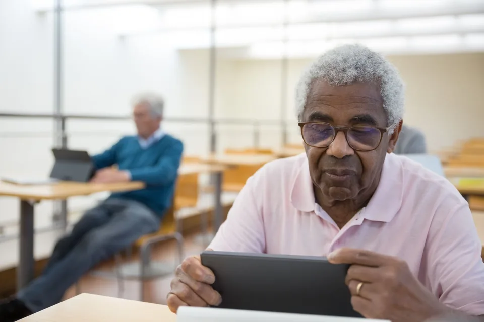An older man using a tablet in a bright room.