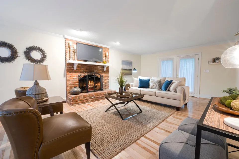 A welcoming sitting room with armchairs, a sofa and a fireplace.