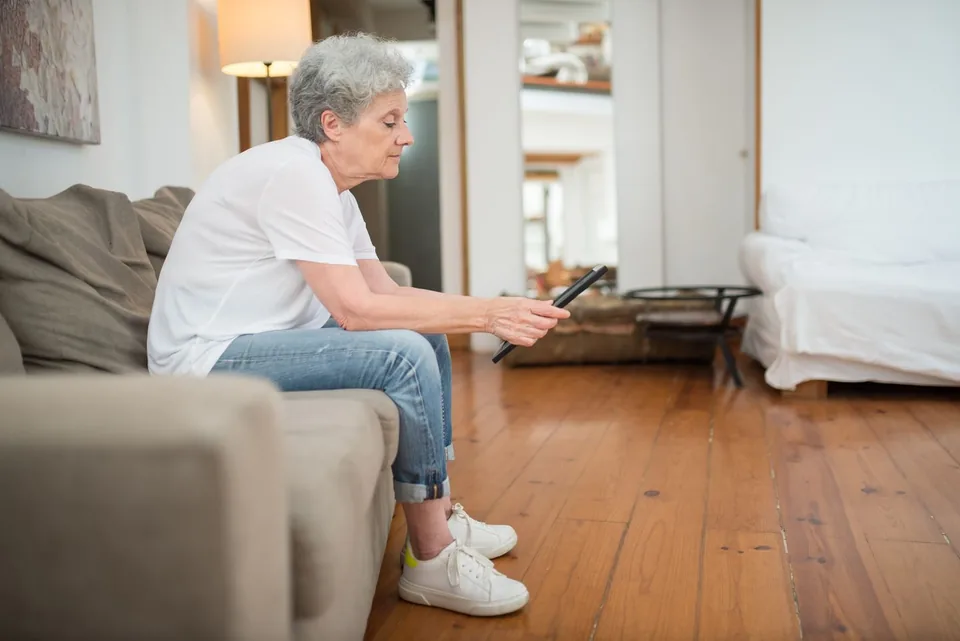 An older woman using a tablet while seated in a living room.